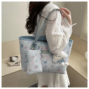 Dettaglio della borsa shopper floreale con trama blu e ciondolo a forma di nuvola