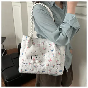Detailed texture of white floral tote bag with cute plush cloud charm on braided strap