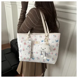 Set borsa tote con stampa floreale e ciondolo indossato sulla spalla del modello