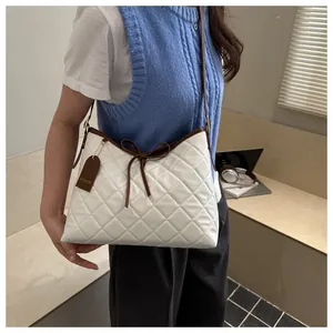 Detail of white quilted handbag with brown bow accent and fashion tag on side