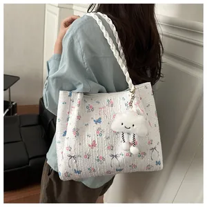 Detail of floral tote bag with blue butterfly patterns and fluffy cloud charm accessory