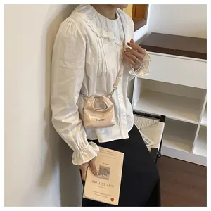 Close-up of a mini pink patent leather bag with Fashion lettering on white lace blouse