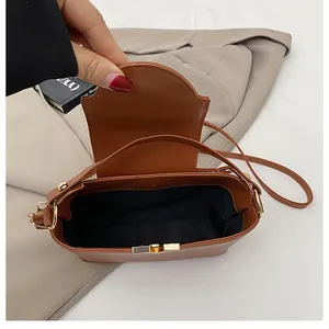 Interior view of small brown bucket bag showing black lining and gold hardware buckle