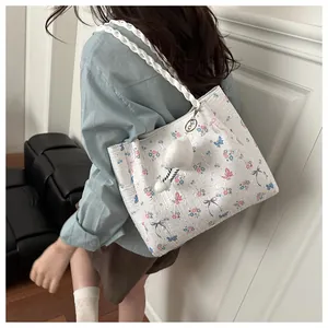 Floral tote bag with woven strap and plush heart charm shown on model in soft interior