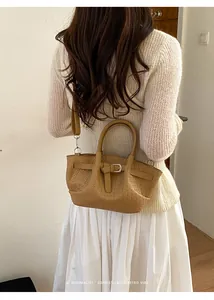 Detail of warm brown woven bucket bag with leather strap shown as a crossbody