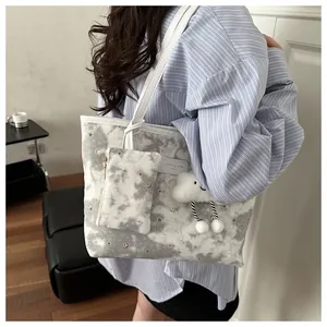 Detail of printed tote bag with matching pouch and plush cloud charm on shoulder
