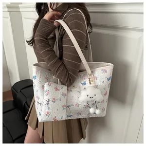 Dettaglio della borsa tote floreale con texture 3D e ciondolo a forma di nuvola