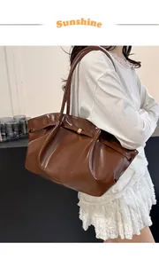 Détail du sac seau en cuir verni marron foncé avec boucle métallique et sangle décorative