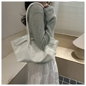 Macro detail of white patent leather tote bag showing stylish pleats and glossy finish