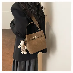 Detailaufnahme der braunen Velours-Eimertasche mit Goldverschluss und Plüschtier
