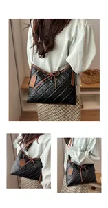 Detail of black quilted shoulder bag with brown leather trim and bow decoration
