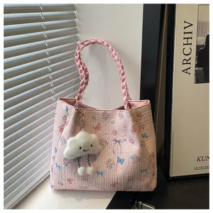 Detail of pink floral tote bag with textured fabric, woven handles and cloud charm