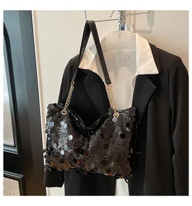 Détail d'un sac cabas à paillettes noires avec bandoulière en chaîne dorée brillante