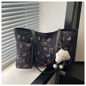 Dettaglio del set borsa tote floreale con texture e ciondolo nuvola sul davanzale