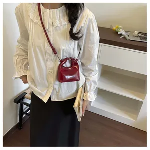 Detailed view of mini red patent leather handbag with adjustable long shoulder strap
