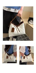 Detail of white quilted tote bag featuring brown leather trim and fashion brand tag