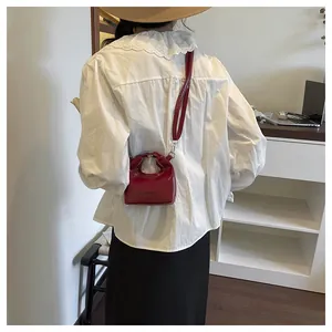 Detailed view of a red patent leather mini tote bag with FASHION lettering and shoulder strap