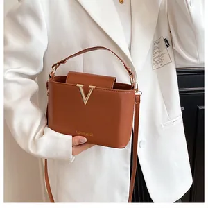 Close-up of brown leather bucket bag featuring a gold V-shaped buckle and strap