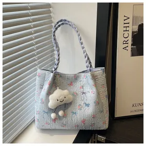 Detail of light blue quilted floral tote bag with braided handles and cloud charm