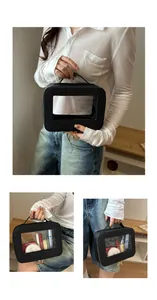 Détail d'une trousse à maquillage en cuir noir avec fenêtre transparente et zips dorés