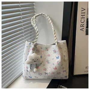 Detail of white floral tote bag with cloud charm and woven handle in natural window light