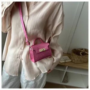 Detail shot of mini magenta square handbag with metallic texture and gold turn-lock