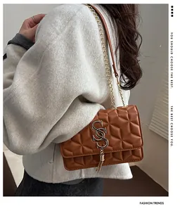 Detail of brown quilted crossbody bag featuring golden logo and metallic tassel accent