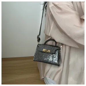 Detail of silver metallic mini handbag featuring a golden clasp and elegant top handle