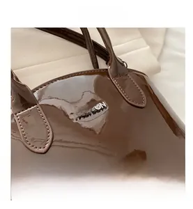 Close-up of coffee brown patent leather handbag featuring silver Fashion metal logo detail