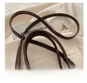 Detail of dark brown patent leather shell bag with glossy handles and silver hardware