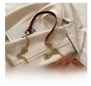 Detail of brown leather handbag with geometric diamond quilting and gold chain strap