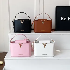 Minimalist bucket style handbag with gold V logo in black brown pink and white colors