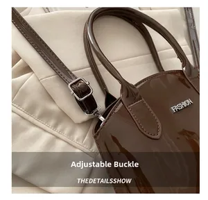 Detail of dark brown patent leather bag with silver buckle and adjustable shoulder strap