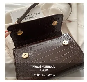Detail shot of dark brown crocodile texture bag featuring dual gold magnetic snaps