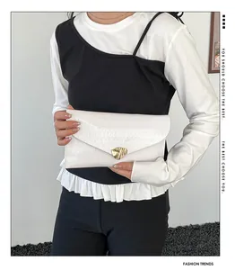 Détail de la pochette enveloppe blanche avec texture gaufrée et boucle dorée ondulée