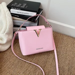 Chic light pink bucket bag with gold V buckle and adjustable strap in lifestyle setting