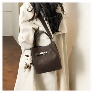 Detail der dunkelbraunen Wildleder-Beuteltasche mit Metallverschluss und Plüsch-Anhänger