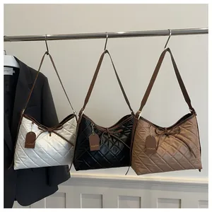 Close-up of quilted tote bags with bow detail and leather tags in black, white, and brown