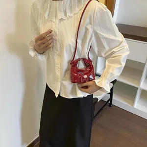 Mini red polka dot crossbody bag with horse embroidery worn with a lace shirt