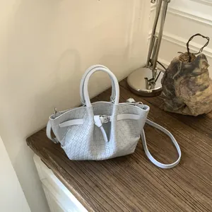 Minimalist light blue woven tote bag with leather strap on a stylish wooden desk setup
