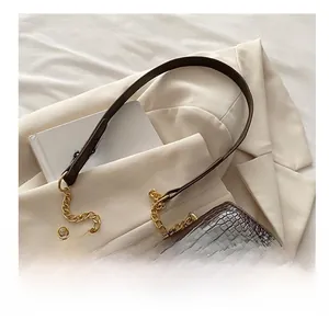 Macro view of dark brown crocodile texture bag with golden bird-shaped buckle detail