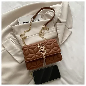 Detail of a brown quilted shoulder bag with golden tassel buckle and chain strap