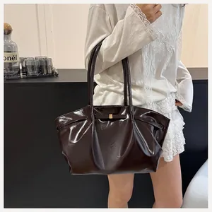 Dettaglio di una borsa tote in pelle verniciata marrone scuro con fibbia e spalline sottili