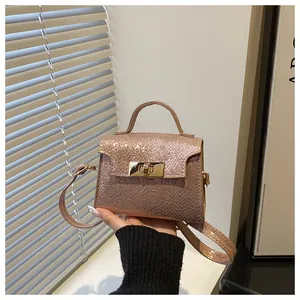 Detail showing rose gold snakeskin texture and metal twist lock on a shoulder bag
