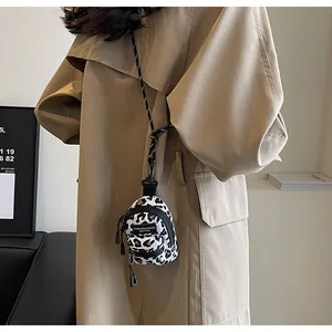 Detailed view of mini leopard print shoulder bag with black strap and dual zippers