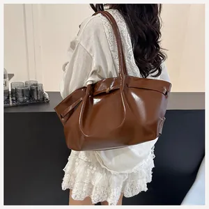 Détail du sac seau en cuir marron foncé brillant avec fine lanière et boucle métallique