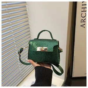 Detail of emerald green snake pattern handbag featuring gold rotating lock and top handle