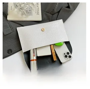 Vue détaillée de la pochette enveloppe blanche avec textures et fermoir magnétique doré