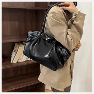 Dettaglio della borsa a spalla nera lucida plissettata con eleganti fibbie oro