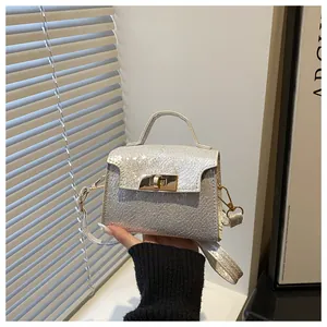 Detail of silver metallic textured mini bag featuring a gold turn-lock and top handle
